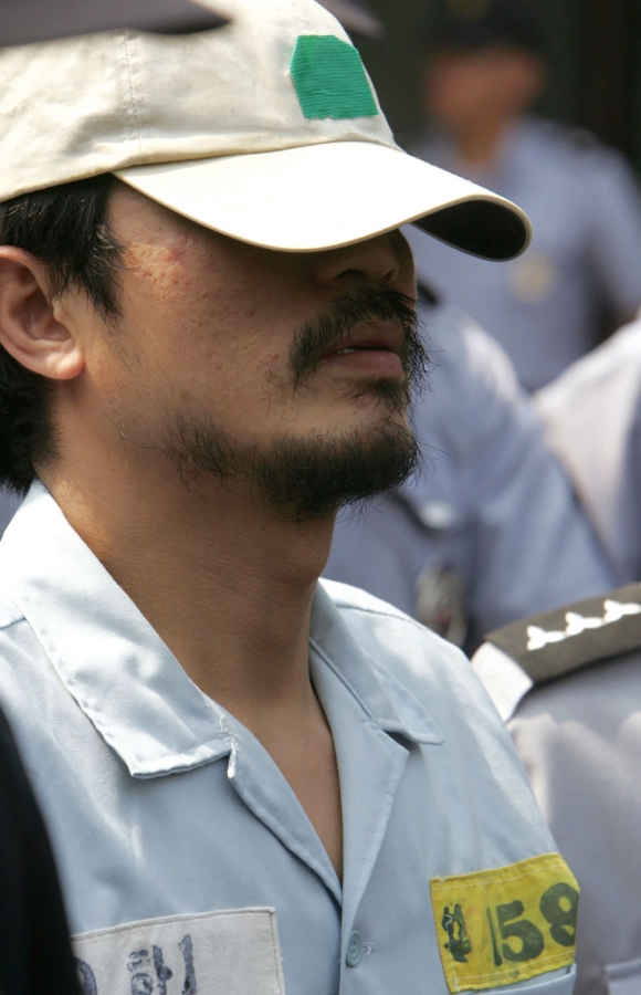 2004년 8월31일 서울 서대문구 봉원사 뒤편 야산에서 연쇄살인범 유영철이 경찰과 검찰 직원들과 함께 자신이 진술한 발굴 작업 현장으로 이동하고 있다. ⓒ 연합뉴스