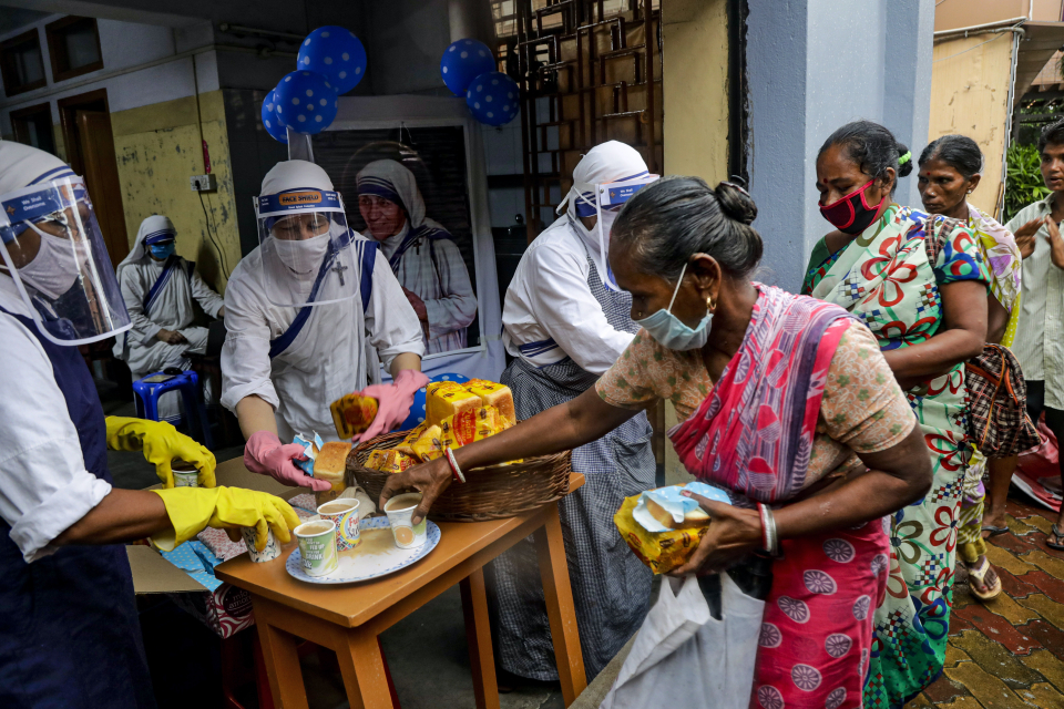 인도 콜카타의 빈민촌에서 '사랑의 선교 수녀회' 소속 수녀들이 코로나19 예방을 위해 마스크를 쓴 채 가난한 사람들과 노숙자들에게 먹을거리를 나눠주고 있다. ⓒ 연합뉴스