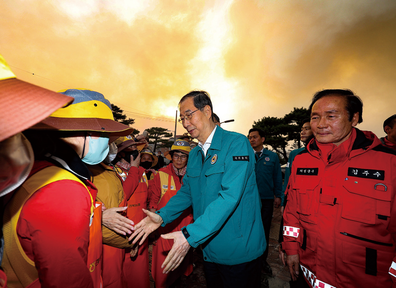 한덕수 대통령 권한대행이 3월24일 경북 의성군 의성체육관에 마련된 산불 대피소를 방문해 봉사자들과 인사하고 있다. ⓒ연합뉴스