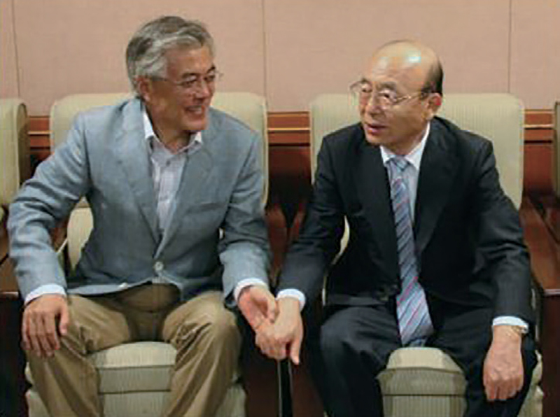 2012년 6월 문재인 전 대통령과 이봉관 회장이 모교인 경희대에서 만나 손을 잡고 있는 모습 ⓒ서희건설 홈페이지